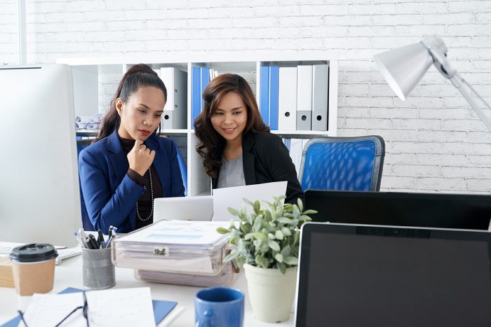 Two Asian Female Colleagues Sitting Together Office Looking Document 1737522251 1738661145